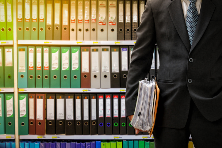 businessman holding data files on binder shelves background