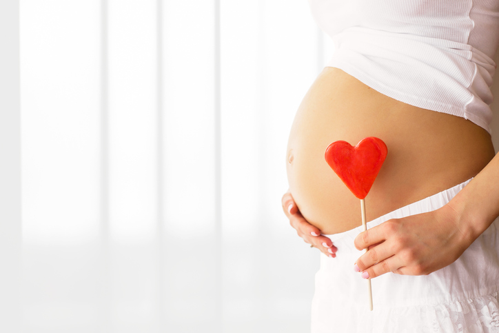 Picture of pregnant woman holding heart sign to one side