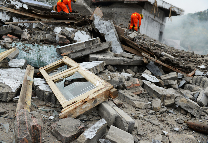 Search and rescue forces search through a destroyed building.