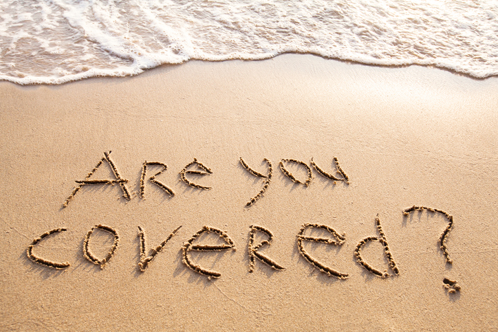 are you covered, travel insurance concept, text on sandy beach