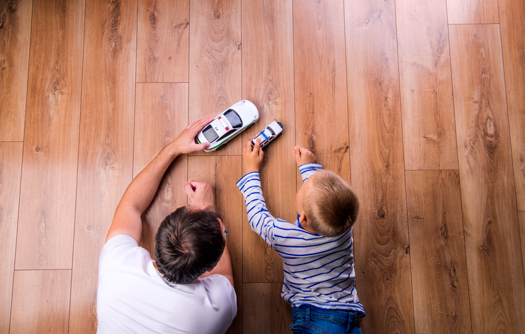 Unrecognizable father with his son playing with cars. Studio shot on wooden background.