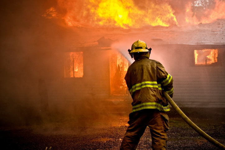 Firefighter spraying water at a house fire