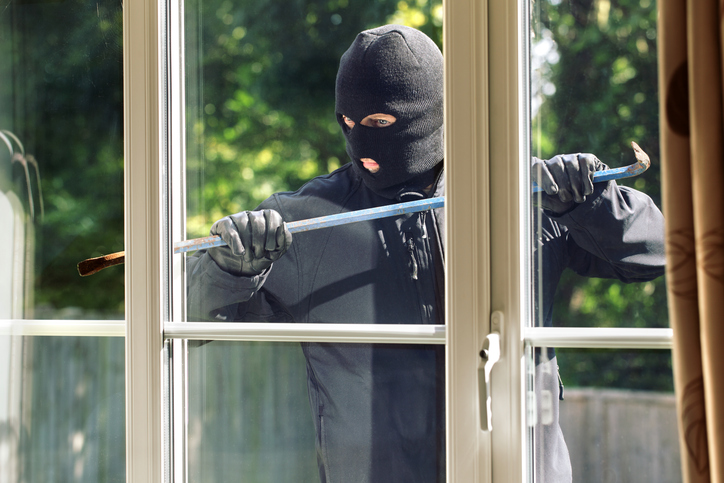 Burglar breaking into a house via a window with a crowbar